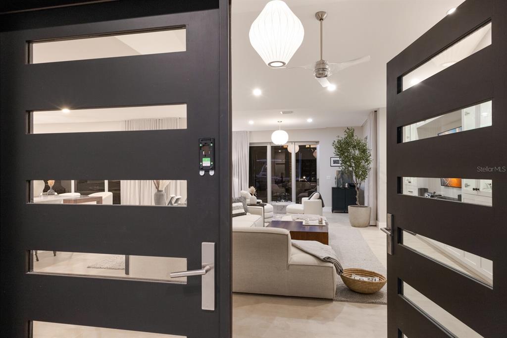A view through an open modern front door into a bright, contemporary living room — 238 ISLAND CIRCLE, SARASOTA, FL