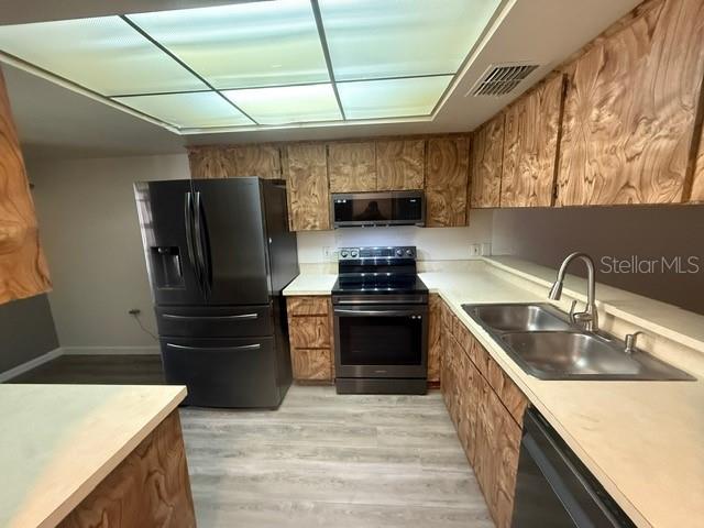 A stainless steel Samsung French door refrigerator stands in a kitchen with wood-patterned cabinets — 2131 RIDGE ROAD S UNIT 74, LARGO, FL