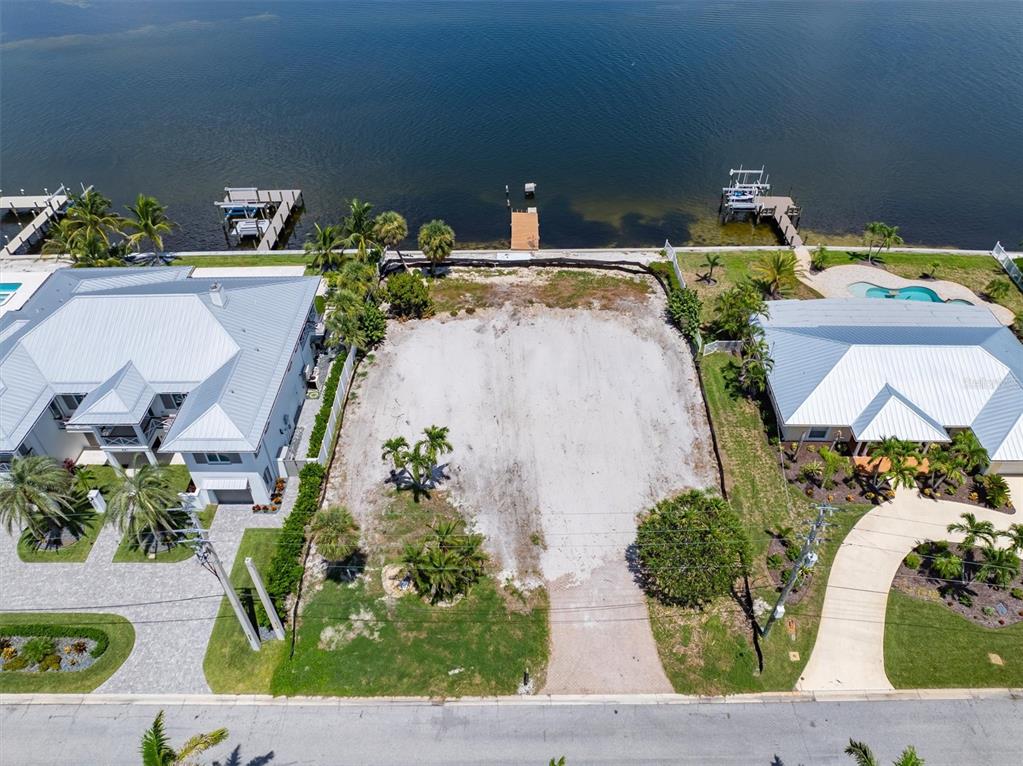 An aerial view shows a vacant waterfront lot situated between two houses with private docks — 659 KEY ROYALE DRIVE, HOLMES BEACH, FL