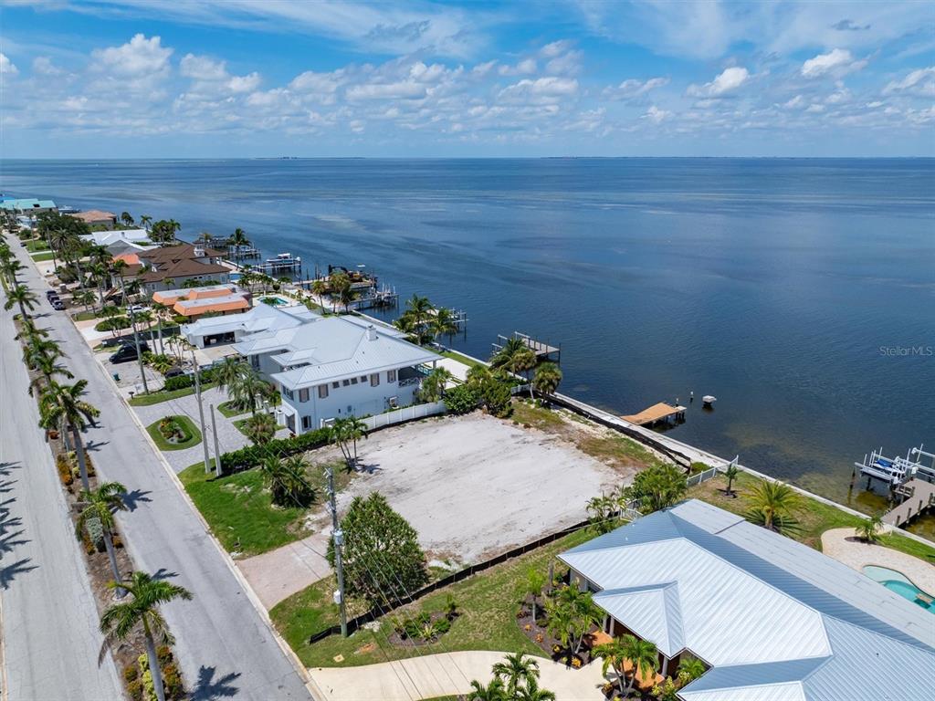 An aerial view shows a vacant waterfront lot situated between two houses along a road — 659 KEY ROYALE DRIVE, HOLMES BEACH, FL