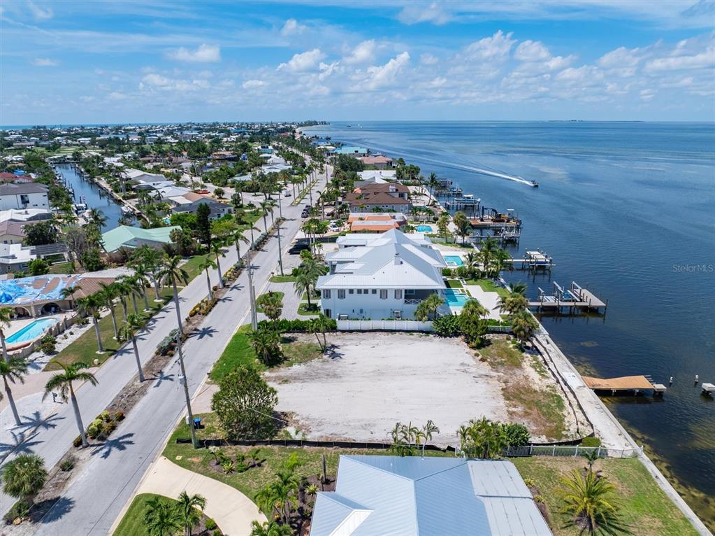 An aerial view shows a vacant waterfront lot situated between a residential street and bay — 659 KEY ROYALE DRIVE, HOLMES BEACH, FL