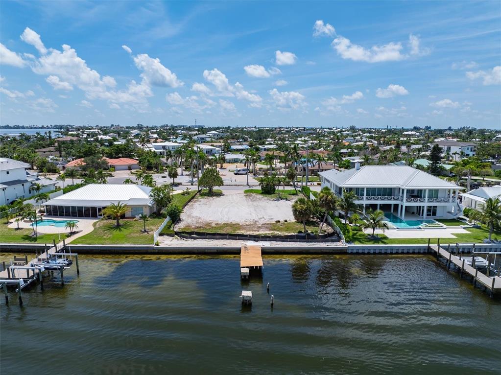 An aerial view shows a vacant waterfront lot situated between two large residential houses — 659 KEY ROYALE DRIVE, HOLMES BEACH, FL