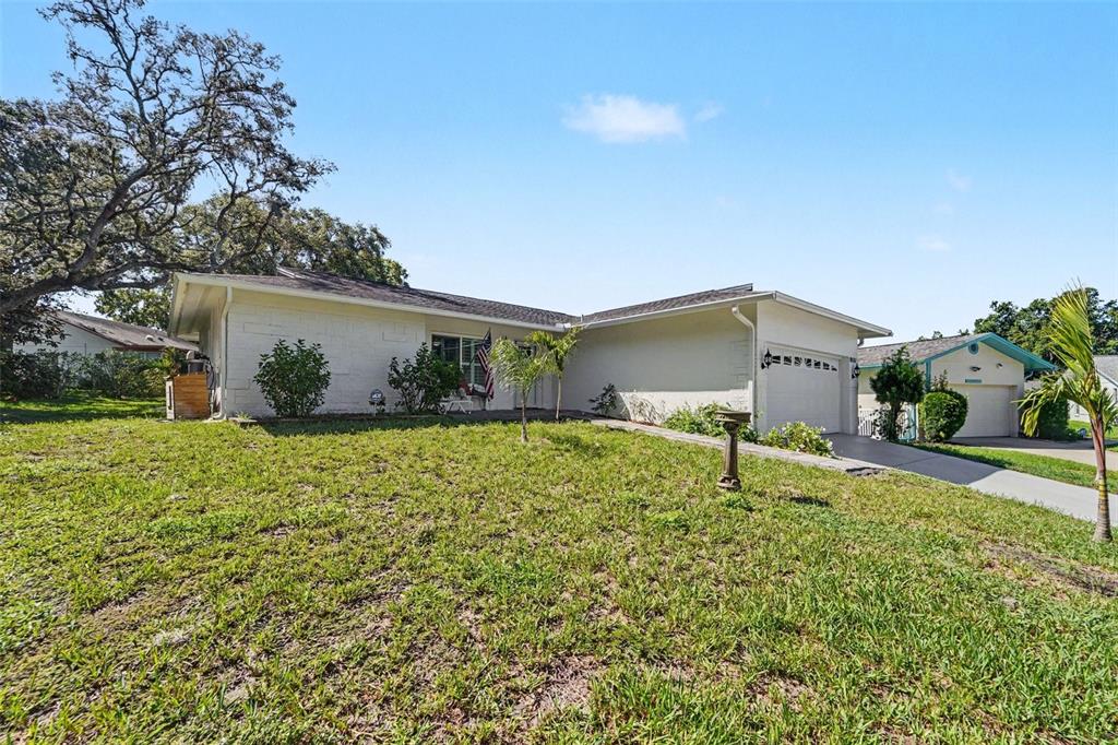 A single-story white house with a garage and a large grassy front yard — 8521 CEDARVIEW COURT, PORT RICHEY, FL