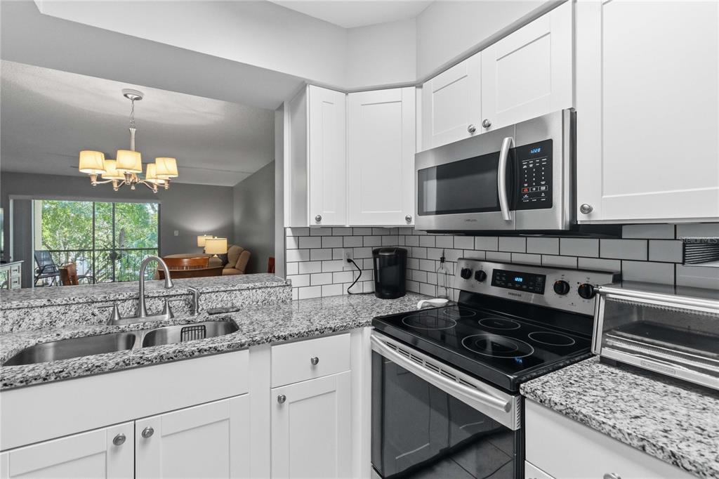 A view of a kitchen with white cabinets and a hallway leading to an entryway — 620 CRANES WAY UNIT 303, ALTAMONTE SPRINGS, FL