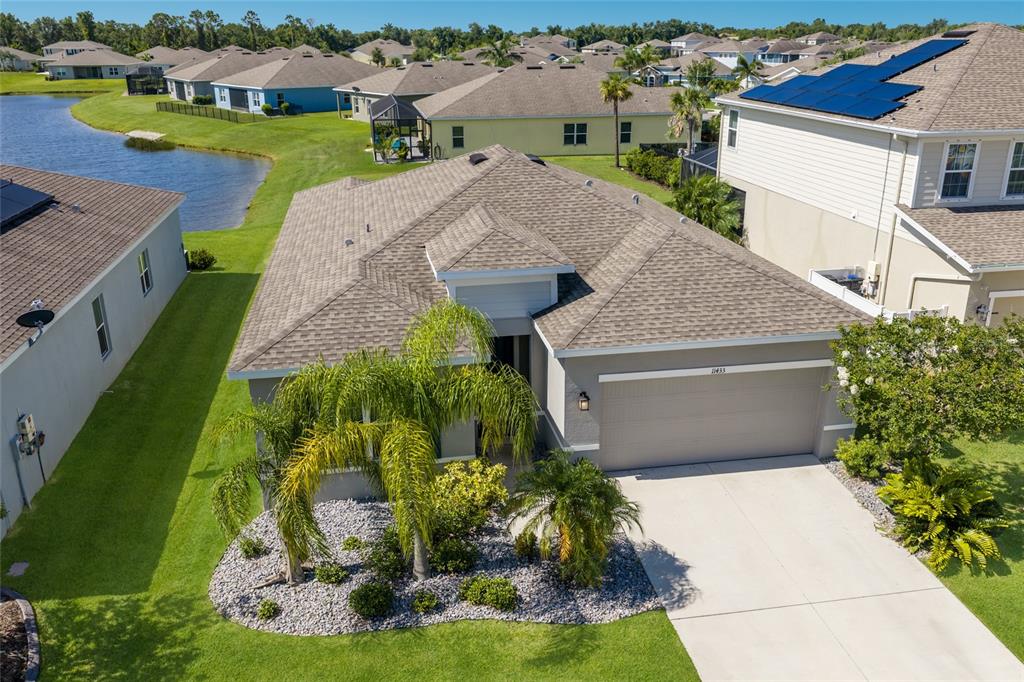 An aerial view shows a single-story suburban house with a gray roof and garage — 11433 64TH STREET E, PARRISH, FL