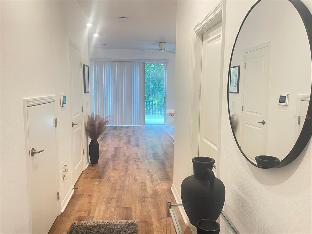 A bright entryway features wood-look flooring, a gray runner rug, and a white front door — 3575 DAVENPORT CREEK COURT, KISSIMMEE, FL