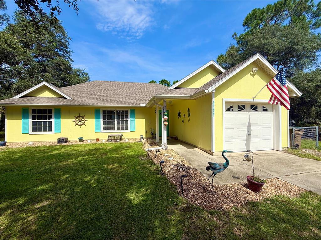 A yellow single-story house with a white garage, turquoise shutters, and a front lawn — 39627 GREENBRIER STREET, EUSTIS, FL