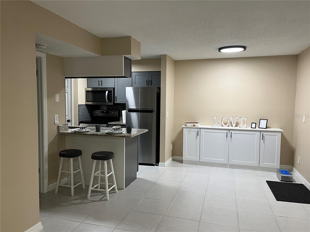 A kitchen features gray cabinets, stainless steel appliances, and speckled granite countertops — 211 THORN TREE PLACE, BRANDON, FL