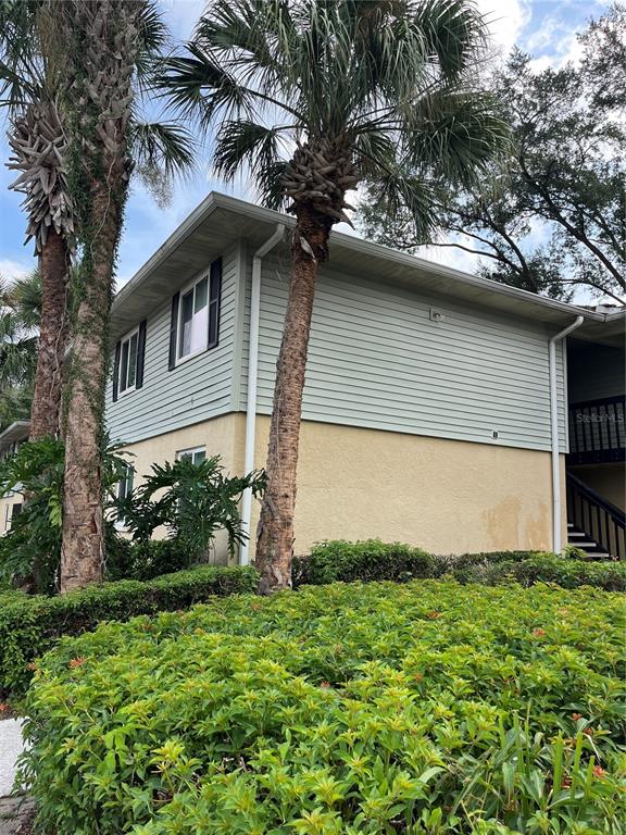 A two-story apartment building exterior features tan stucco, light green siding, and reserved parking spaces — 211 THORN TREE PLACE, BRANDON, FL