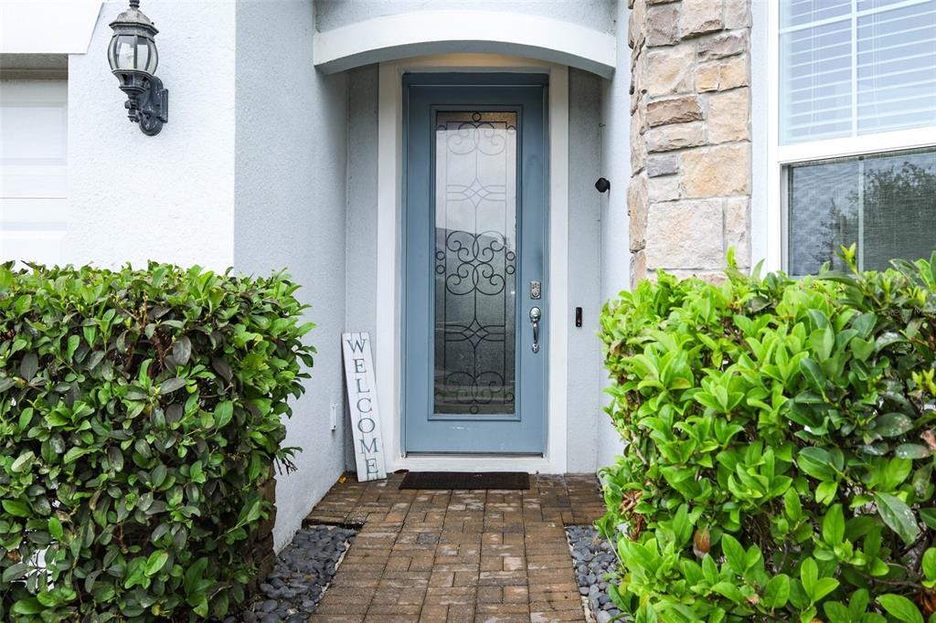 A blue front door with a glass insert sits between two green bushes — 2190 BUR OAK BLVD, ST CLOUD, FL