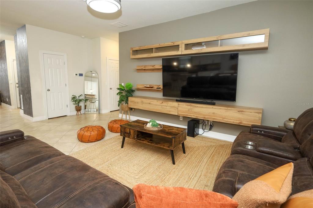 A living room features brown leather sofas, a wood coffee table, and a wall-mounted television — 2190 BUR OAK BLVD, ST CLOUD, FL