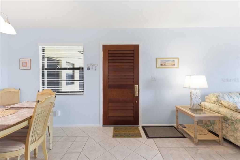 A dining and living area features light blue walls, tile flooring, and a wooden front door — 66 BOUNDARY BOULEVARD UNIT 233, ROTONDA WEST, FL