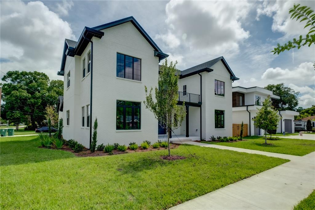 A two-story white farmhouse with a large covered porch, wooden pillars, and a detached garage — 805 W INDIANA AVENUE, TAMPA, FL
