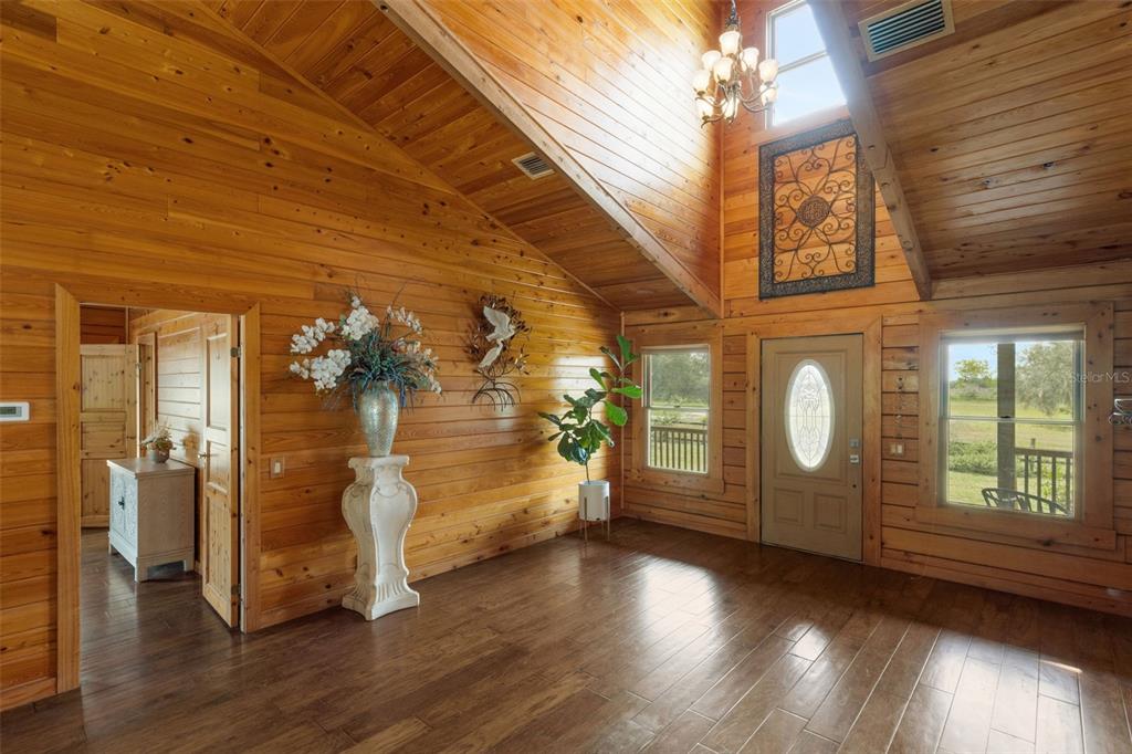 A rustic living room features wood-paneled walls, a vaulted ceiling, and a front entryway — 39730 CARLTON ROAD, PARRISH, FL