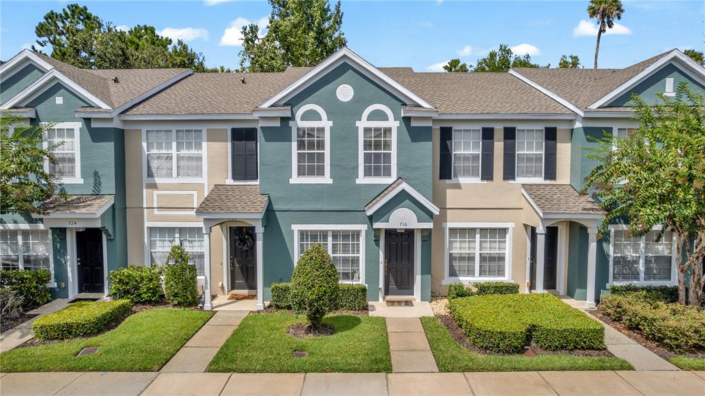 A row of multi-story townhouses with teal and beige siding, gabled roofs, and small front lawns — 716 SHROPSHIRE LOOP, SANFORD, FL