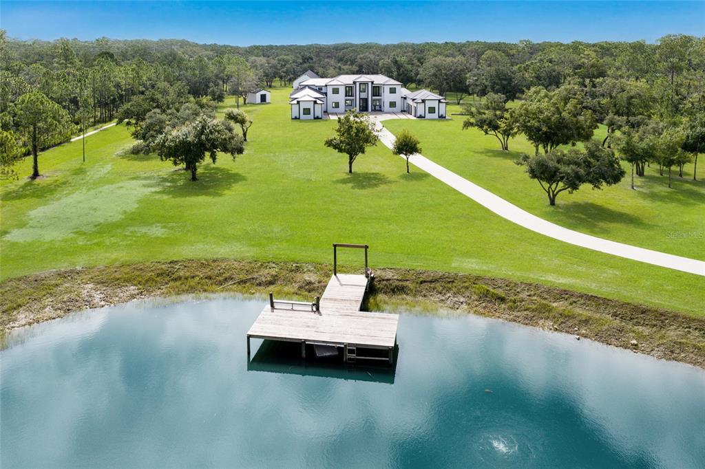 An aerial view shows a large house with a long driveway and a wooden dock — 20307 74TH AVENUE E, BRADENTON, FL