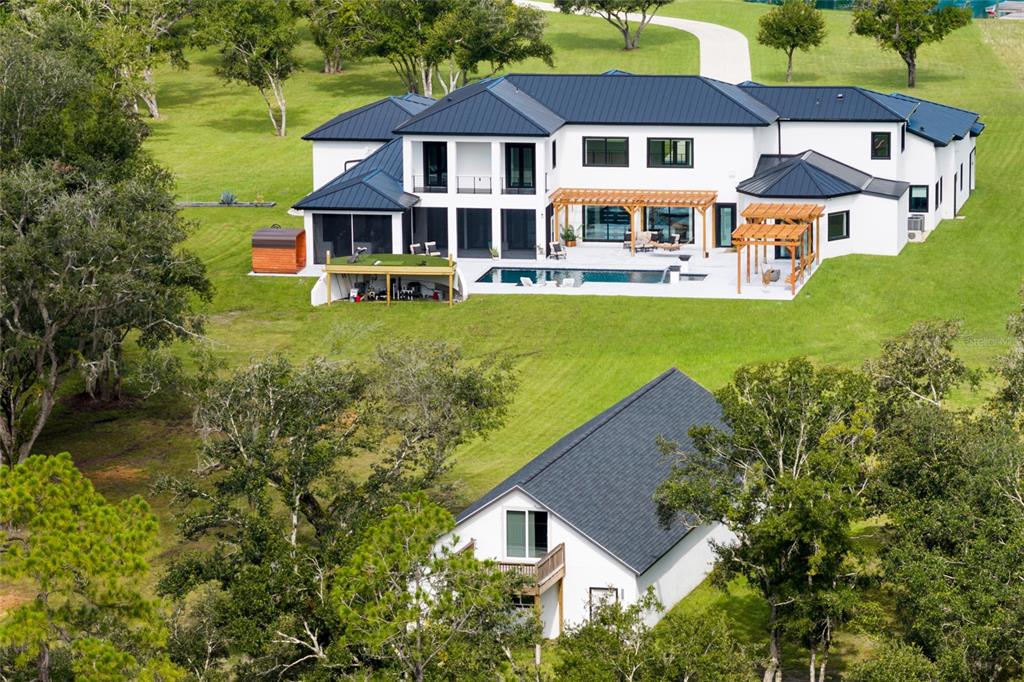 An aerial view of a large white modern house with a pool and detached garage — 20307 74TH AVENUE E, BRADENTON, FL