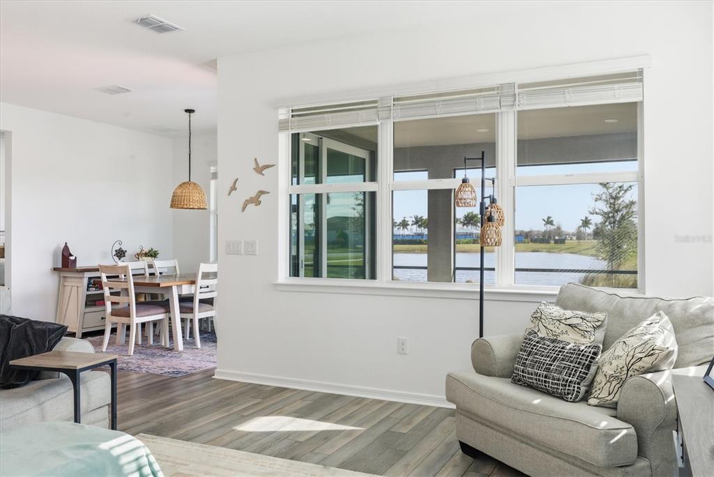A living room with wood-look flooring features a large window overlooking a lake — 8705 COASTAL KEY WAY, PARRISH, FL