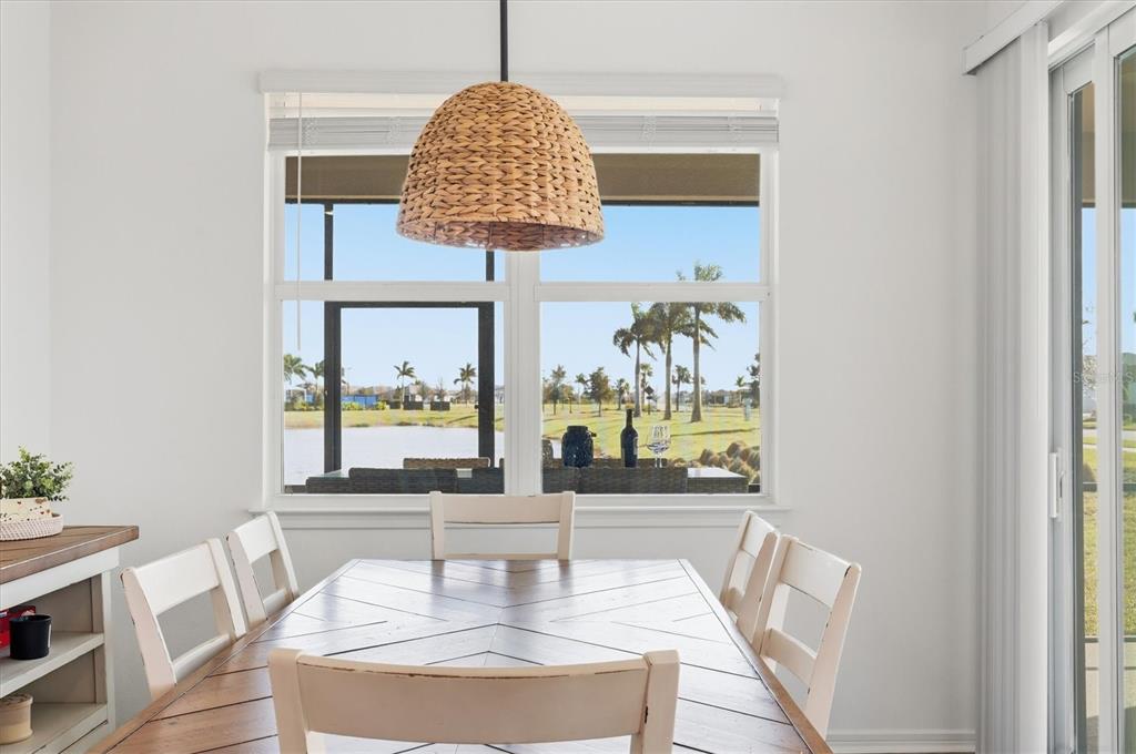 A dining room features a wooden table, white chairs, and a woven pendant light fixture — 8705 COASTAL KEY WAY, PARRISH, FL
