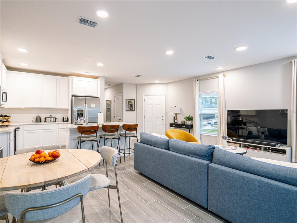 An open-concept kitchen and living area features white cabinetry, a breakfast bar, and blue seating — 4902 LIVINGSTON LANE, OVIEDO, FL