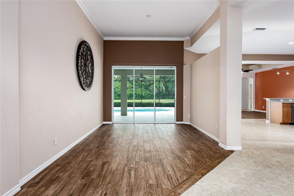 A dining area with wood-look tile flooring, a dark accent wall, and sliding glass doors — 5375 90TH AVENUE CIRCLE E, PARRISH, FL