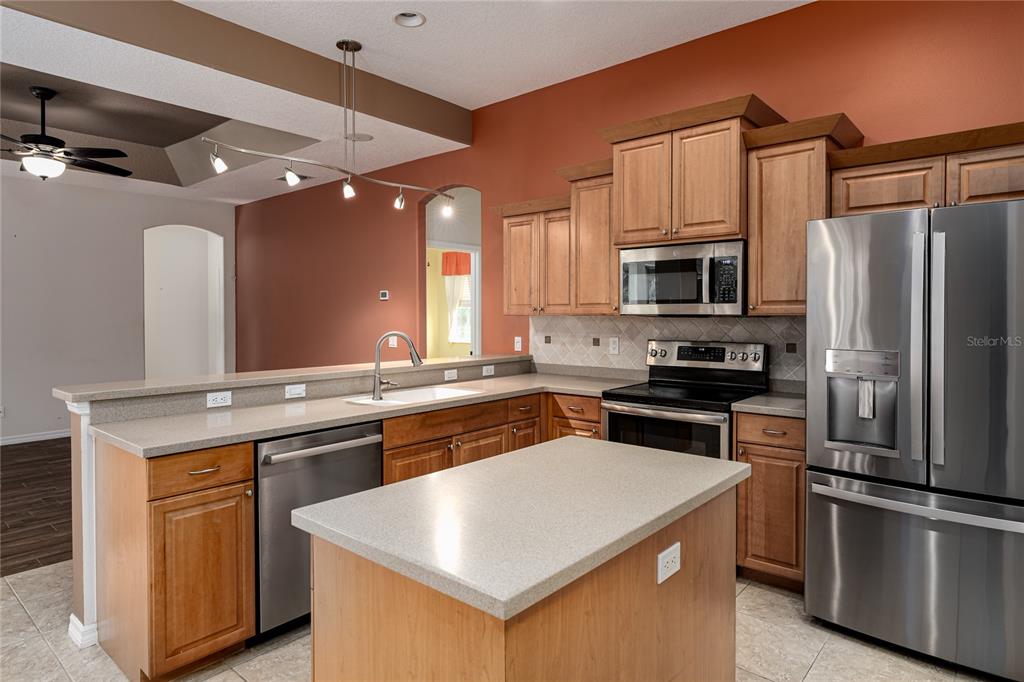 A kitchen features wood cabinets, stainless steel appliances, a center island, and a breakfast bar — 5375 90TH AVENUE CIRCLE E, PARRISH, FL