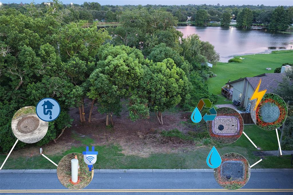 An aerial view of a vacant lot featuring utility access points and a nearby lake — 233 SECRET WAY, CASSELBERRY, FL