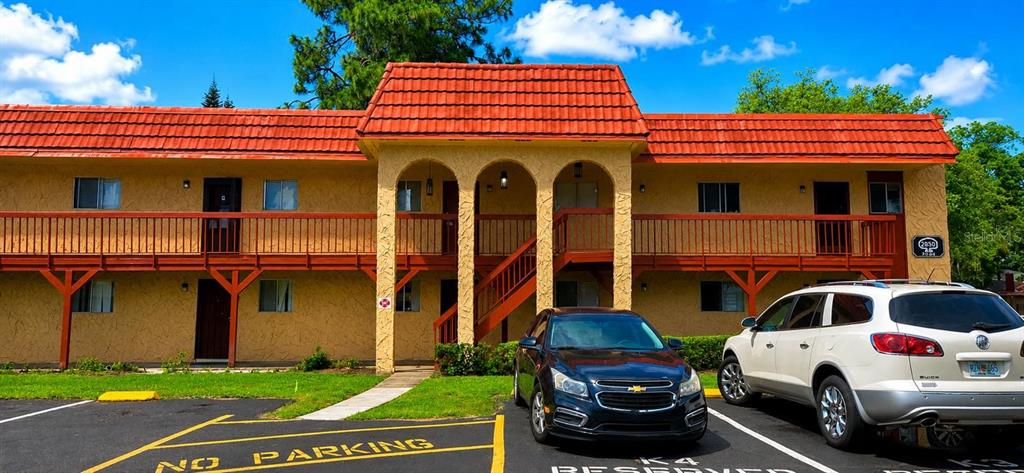 A two-story apartment building with a red tile roof and a parking lot in front — 2850 N POWERS DRIVE UNIT 83, ORLANDO, FL