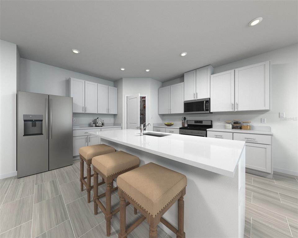 A modern kitchen features white cabinets, stainless steel appliances, a central island, and tiled flooring — 1688 COOLRIDGE PLACE, ZEPHYRHILLS, FL