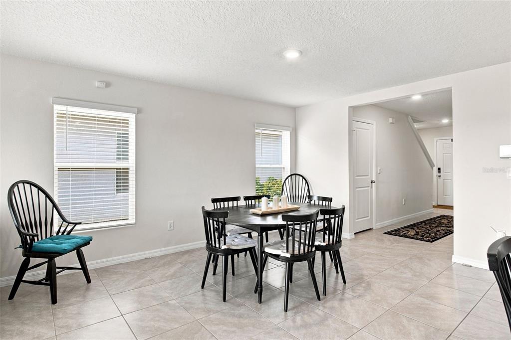 A dining area features a round black table with chairs, tile flooring, and two windows — 6118 DISTANT HAZE PLACE, PALMETTO, FL