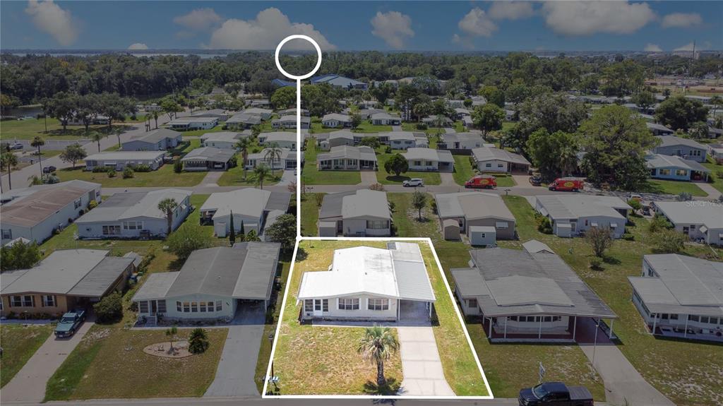 A single-story manufactured home with a beige exterior, a front carport, and a grassy yard — 1207 APACHE CIRCLE, TAVARES, FL