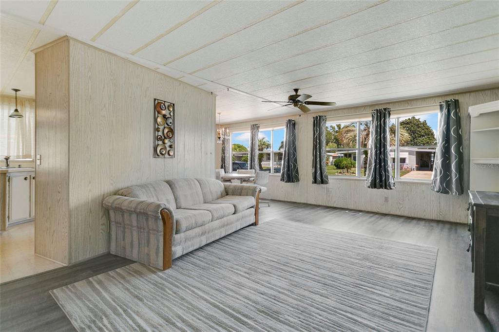 A living room features wood-paneled walls, light gray flooring, a ceiling fan, and sliding glass doors — 1207 APACHE CIRCLE, TAVARES, FL