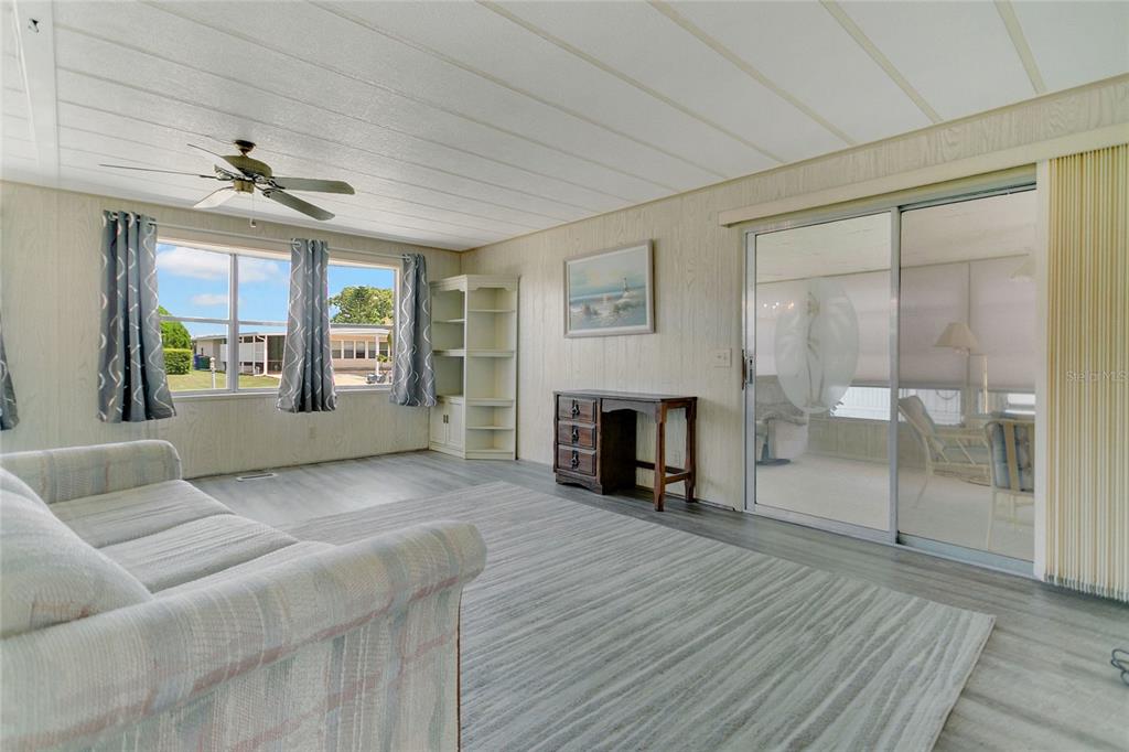 A living room with wood-paneled walls, a gray sofa, and a large area rug — 1207 APACHE CIRCLE, TAVARES, FL