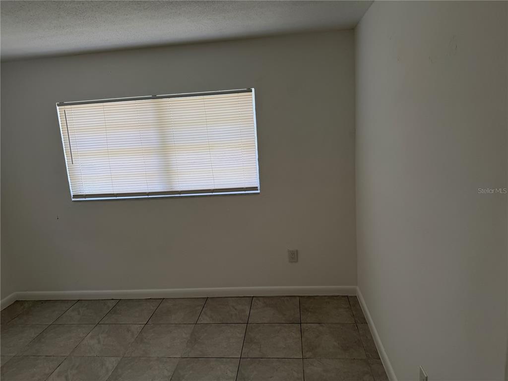 An empty room features white walls, a single window with blinds, and tiled flooring — 1531 NE 14TH STREET, OKEECHOBEE, FL
