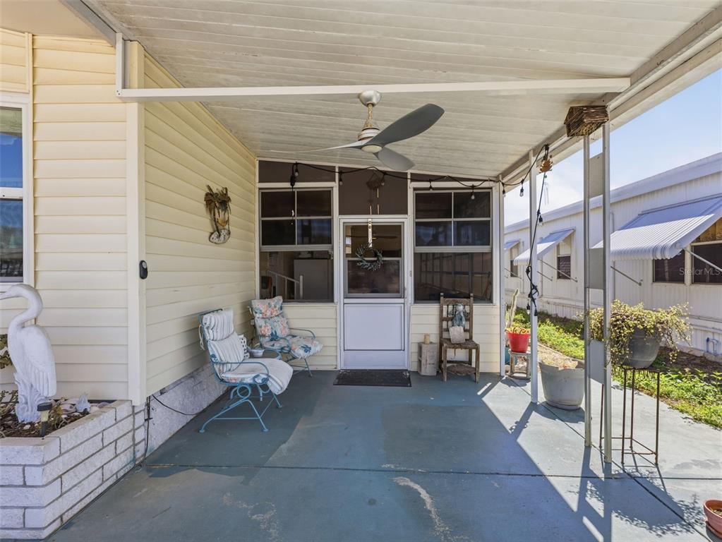 A covered patio features a ceiling fan, light strings, and outdoor seating — 7402 CASCADE DRIVE, HUDSON, FL