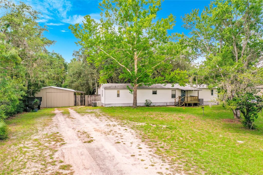 A single-story manufactured home with a metal roof, front porch, and detached garage — 31032 RORY LANE, EUSTIS, FL