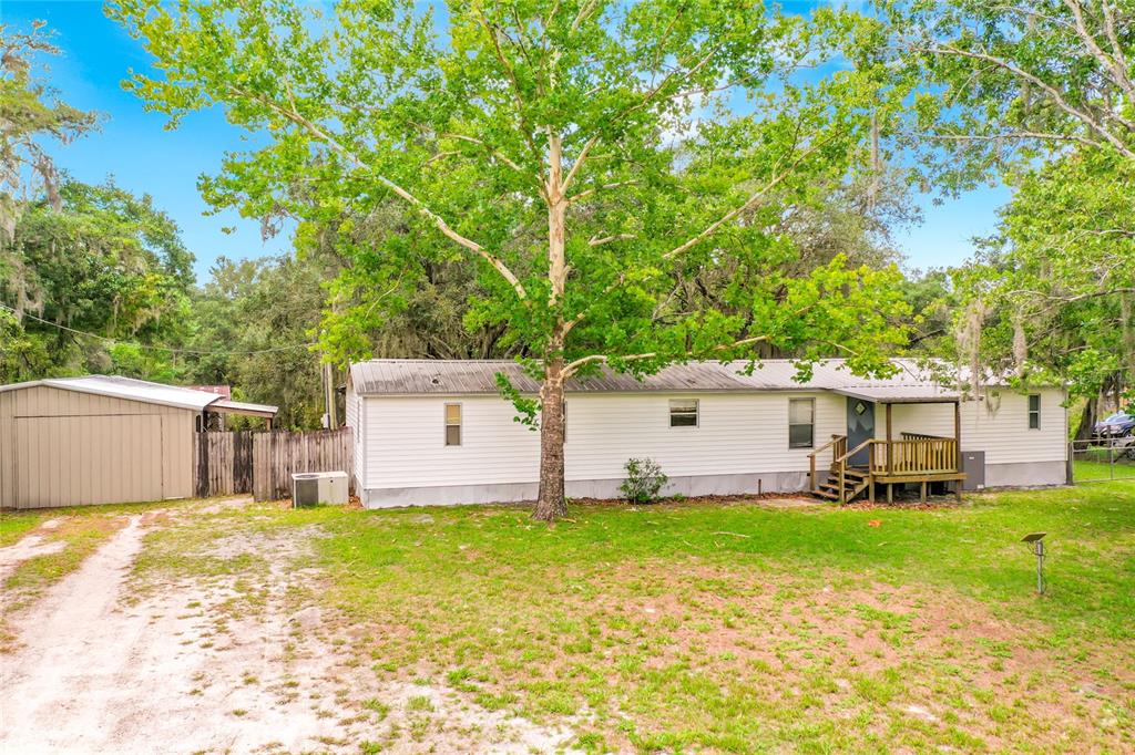 A single-story mobile home with white siding, a metal roof, and a small wooden porch — 31032 RORY LANE, EUSTIS, FL