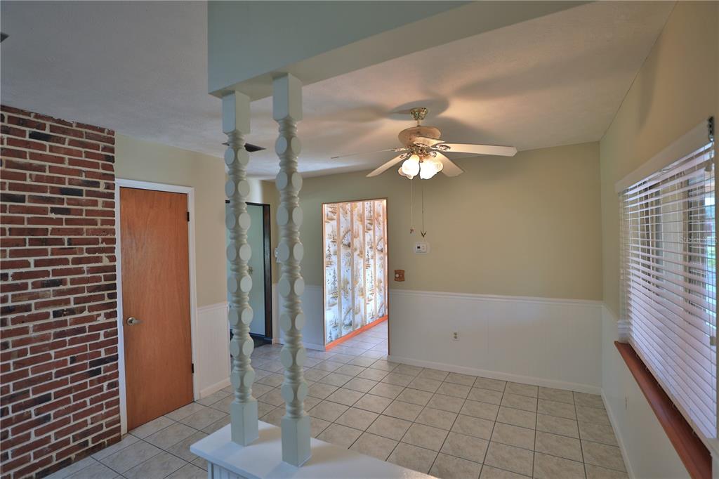 A room with tile flooring, a ceiling fan, a brick wall, and decorative wooden columns — 2155 SE COUNTY HIGHWAY 484, BELLEVIEW, FL