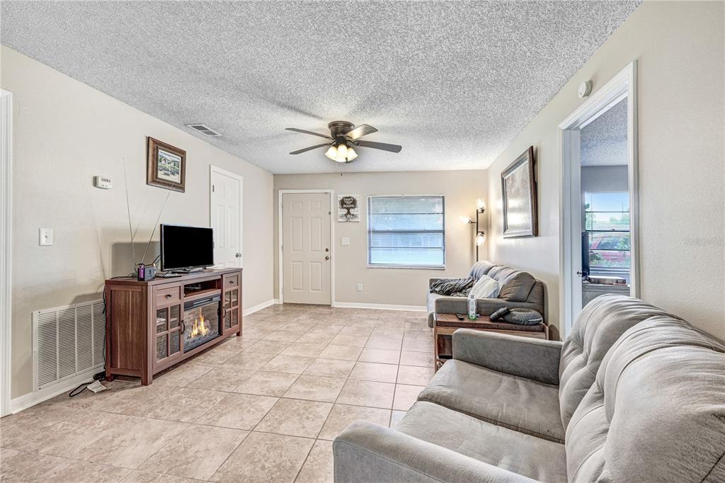 A living room features tile flooring, a ceiling fan, a fireplace console, and two sofas — 2442 DIANNE DRIVE, COCOA, FL