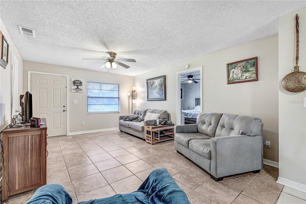 A living room features tile flooring, two gray sofas, and a ceiling fan — 2442 DIANNE DRIVE, COCOA, FL