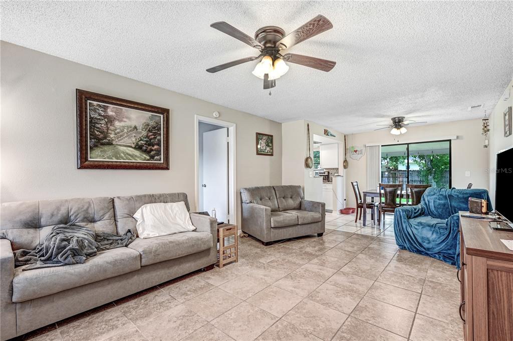 A living room features tile flooring, two gray sofas, a blue chair, and ceiling fans — 2442 DIANNE DRIVE, COCOA, FL