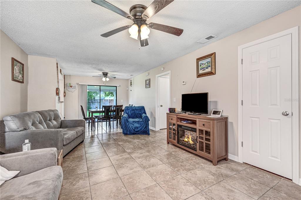 A living room with tile flooring, a ceiling fan, a fireplace console, and dining area — 2442 DIANNE DRIVE, COCOA, FL