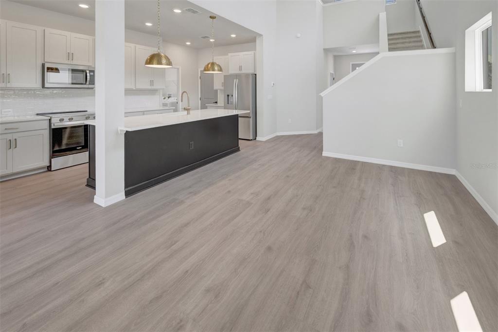 A modern kitchen with white cabinets, a dark island, and light wood-look flooring — 15239 EASTLYN DRIVE, BRADENTON, FL