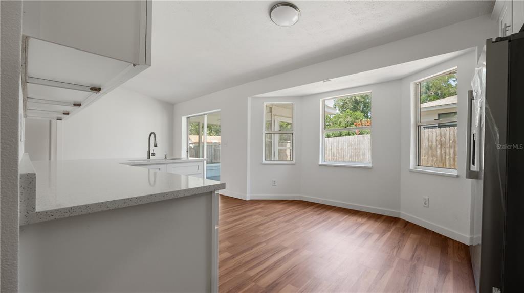 A kitchen and dining area with white cabinets, quartz countertops, and wood-look flooring — 34691 ORCHID PARKWAY, DADE CITY, FL
