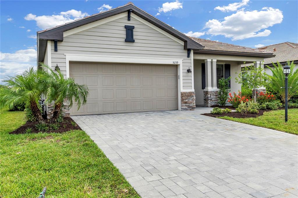 A single-story house exterior features a beige garage, stone accents, and a paved driveway — 5239 CORAL REEF WAY, BRADENTON, FL