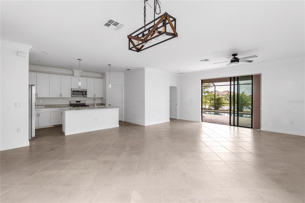 An open-concept kitchen and living area features white cabinetry, tile flooring, and sliding glass doors — 5239 CORAL REEF WAY, BRADENTON, FL