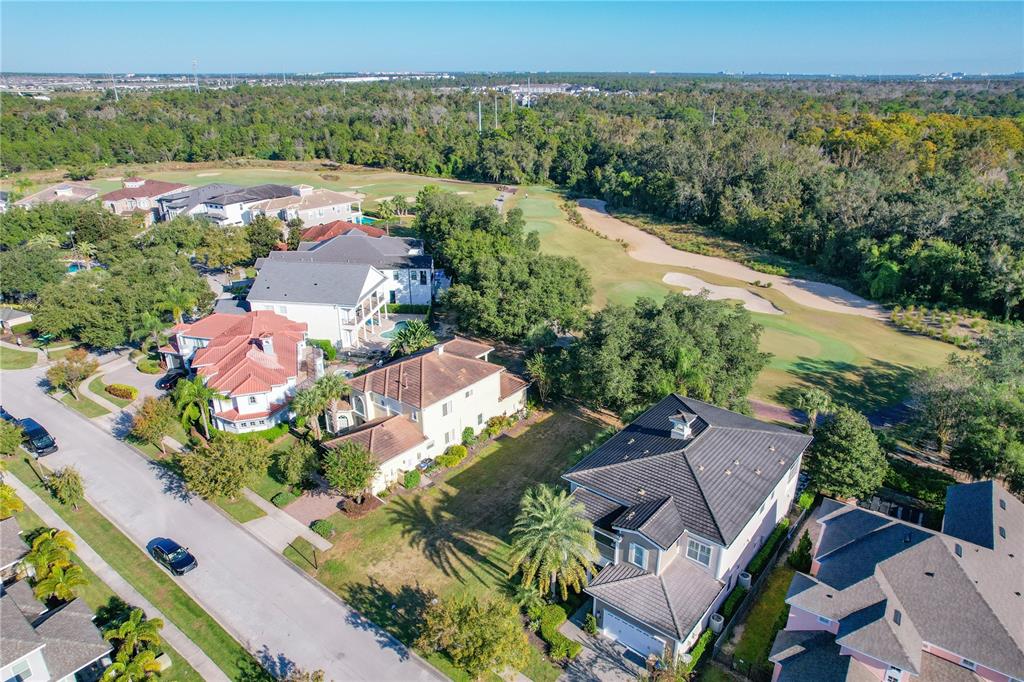 An aerial view shows a vacant rectangular lot situated between two large residential homes — 7455 GATHERING DRIVE, KISSIMMEE, FL