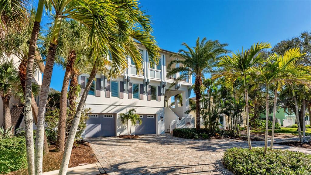 A three-story house with a paved driveway and palm trees under a clear blue sky — 1013 ELDORADO AVENUE, CLEARWATER, FL