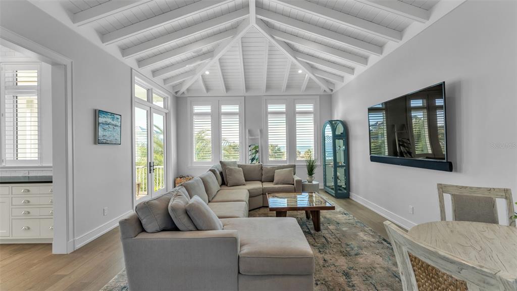 A living room features a vaulted white ceiling, a large sectional sofa, and a television — 1013 ELDORADO AVENUE, CLEARWATER, FL