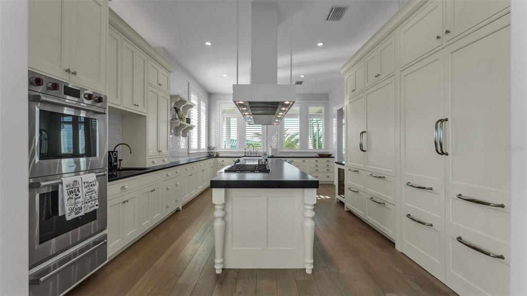 A bright kitchen features white cabinetry, a central island with a cooktop, and stainless appliances — 1013 ELDORADO AVENUE, CLEARWATER, FL